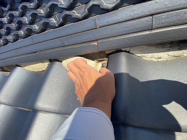 大棟の漆喰の状態を手で触れて確認中